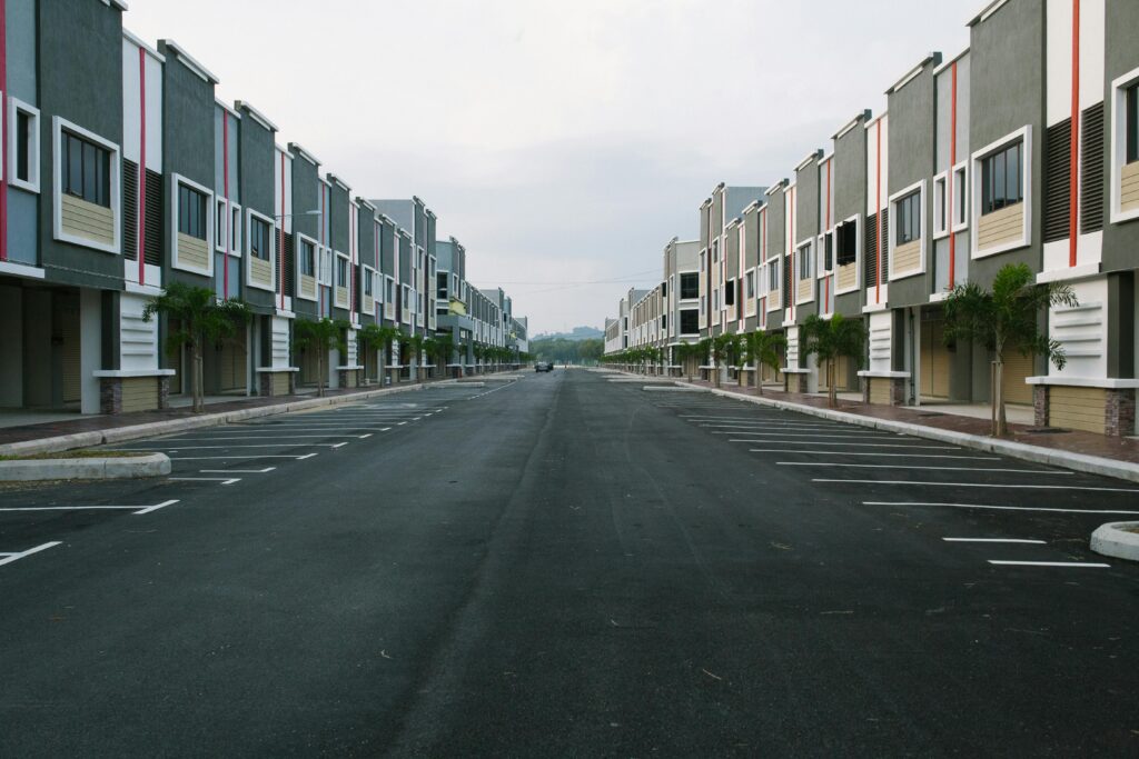 pexels-photo-250659-250659 A quiet, empty urban street flanked by modern condominiums under a cloudy sky, with ample parking space.