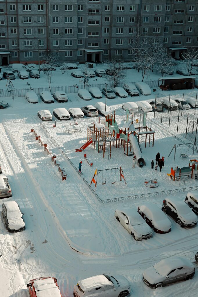 Aerial view of a snow-covered playground and parking lot during winter.